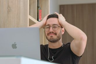 a man with glasses is looking at a laptop