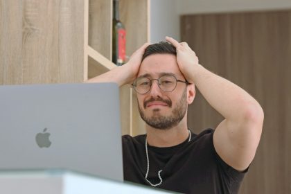 a man with glasses is looking at a laptop